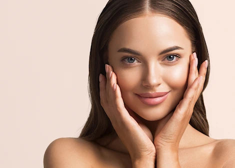 Woman with smooth skin touching her face against a beige background