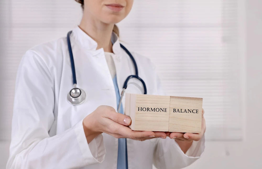female doctor holding wooden blocks indicating HORMONE BALANCE white coat and a stethoscope white background
